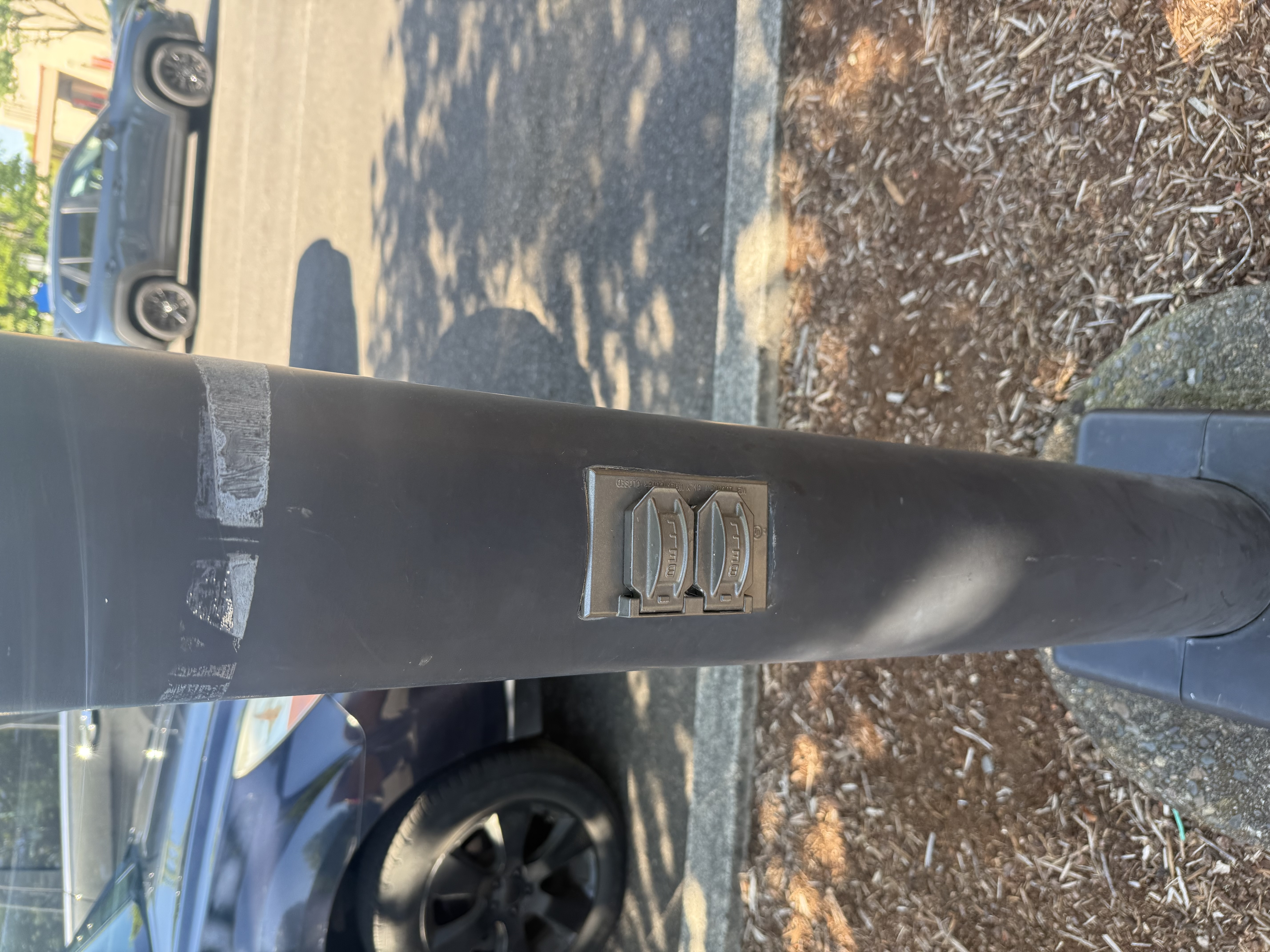 Close-up of the exterior drinking fountain fixture — chrome double-spout mounted on a dark post near the library entrance