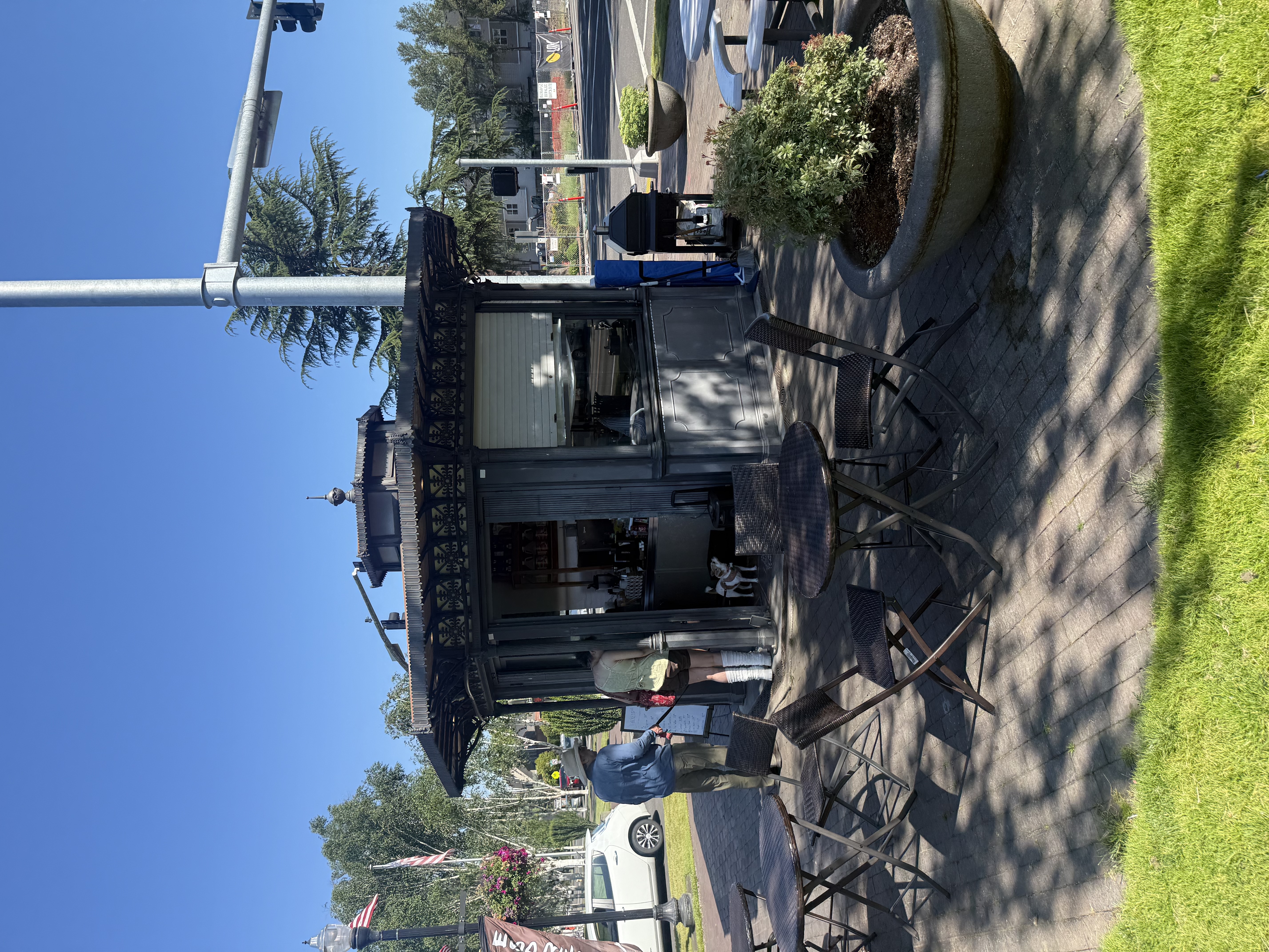 The small permanent kiosk adjacent to the splash pad — dark painted wood structure with outdoor seating and planters