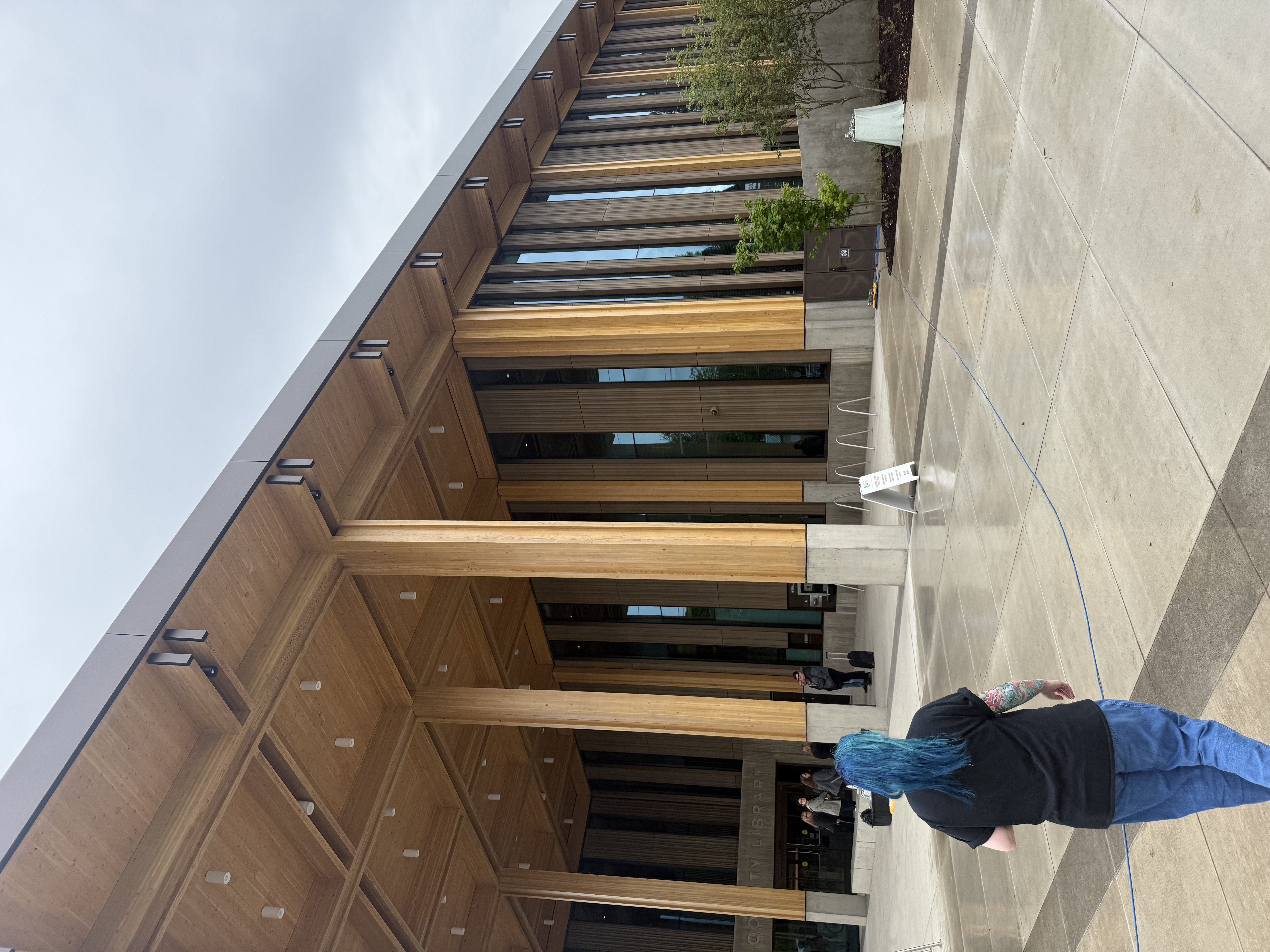 Close view of the library façade showing alternating light and dark wood vertical fins with floor-to-ceiling glazing