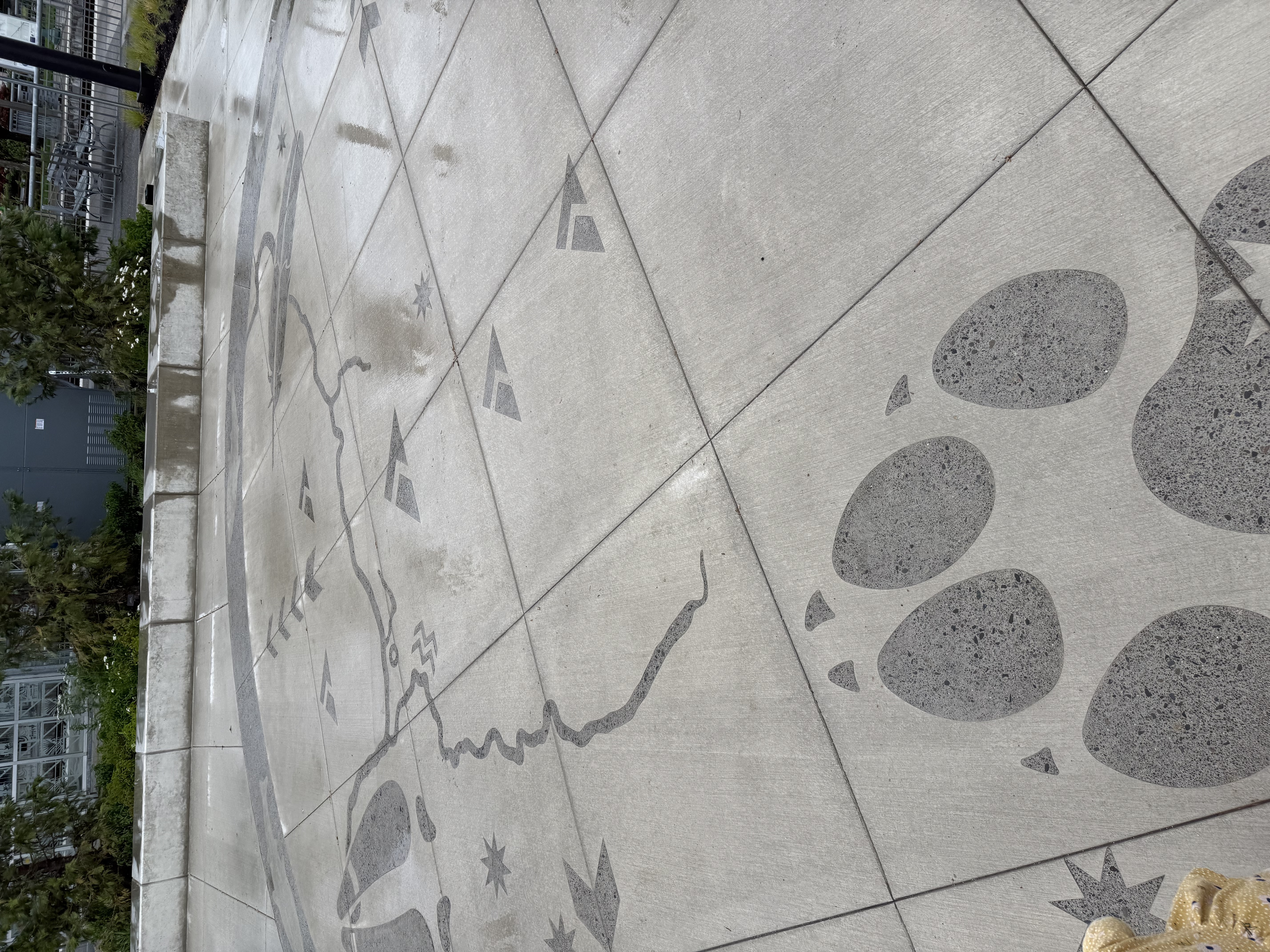 Decorative etched bear paw prints and river map motif in the concrete patio surface, with a child touching the design