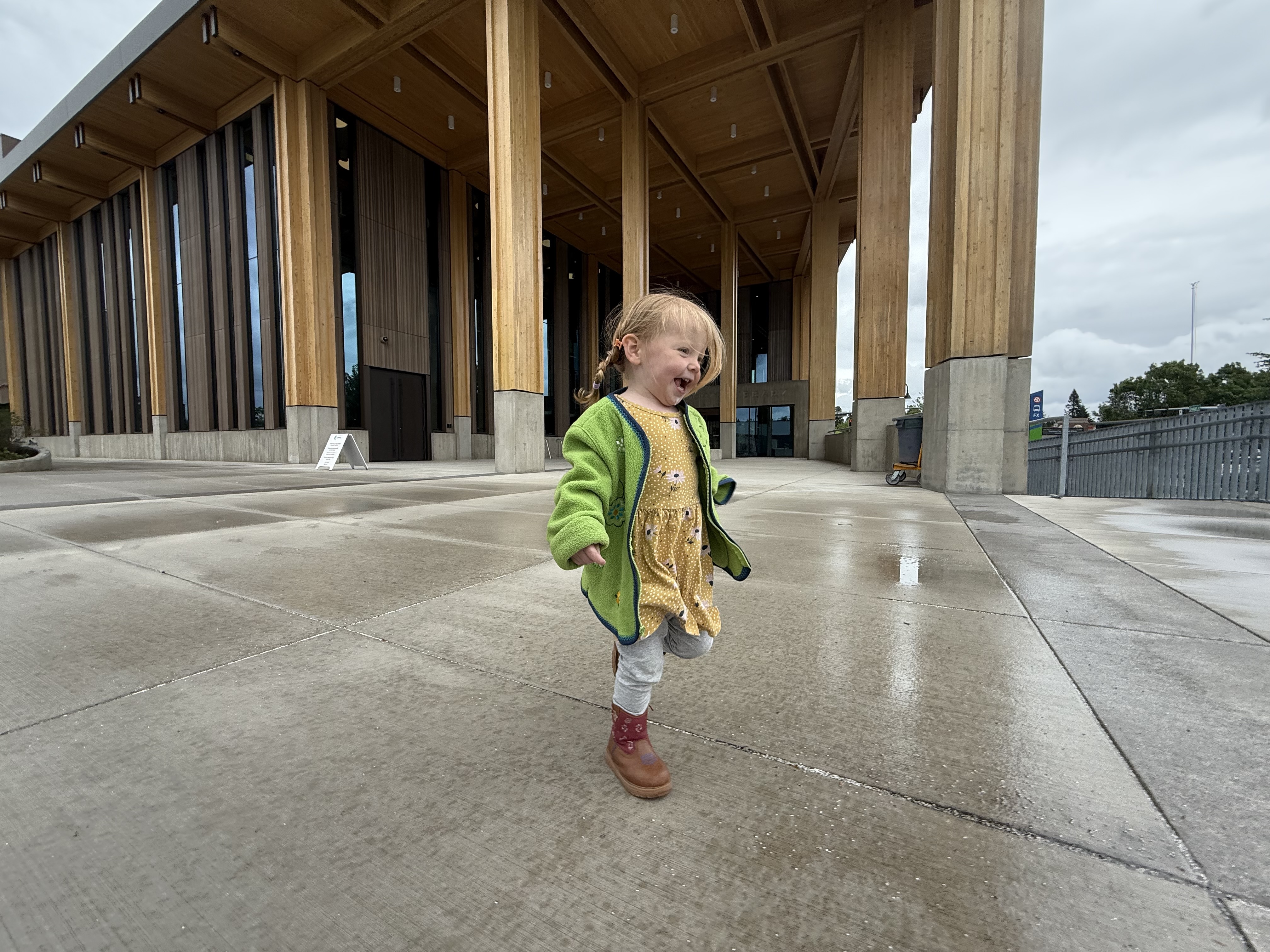 Toddler running on the large new concrete patio with the timber pavilion visible behind